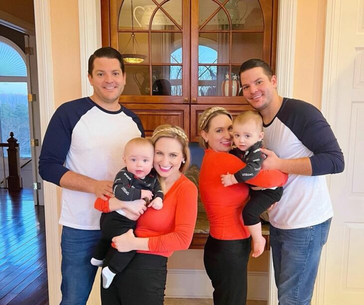 women carrying their babies next to their husbands in front of the facade of a house 