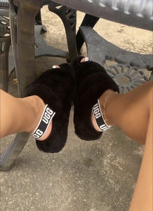 pies de una chica usando una pantuflas furry UGG en color negro 