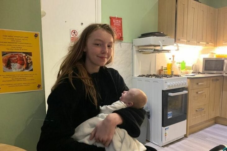 chica con su bebé en brazos en una cocina