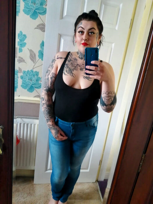 photo of a woman in front of the mirror showing her tattoos 