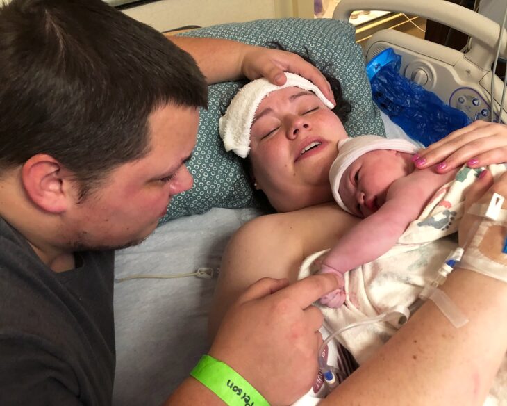 mujer con su bebé recién nacida a lado de su esposo en el hospital 