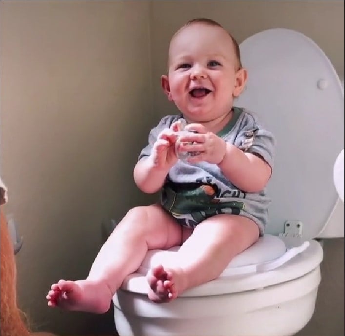 bebé sonriendo sentado sobre un inodoro