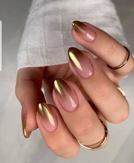 Chica usando unas uñas con tonos dorados brillantes 