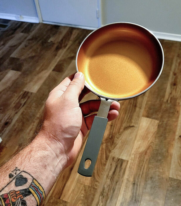 A man's hand holding a frying pan