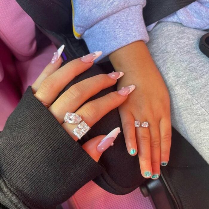 Manos de Kylie Jenner y Stormi Webster mostrando sus anillos
