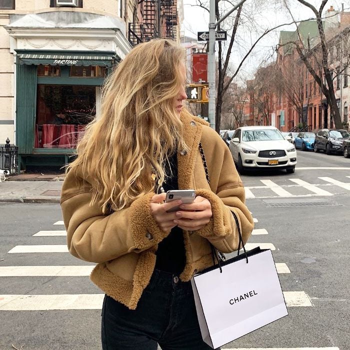 Chica posando con una bolsa de Chanel frente a una calle de cruce 