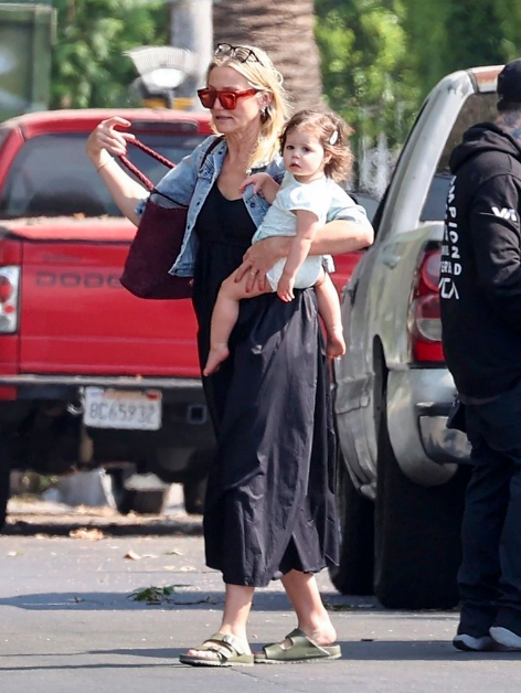 Cameron Díaz cargando a su hija cruzando una calle 