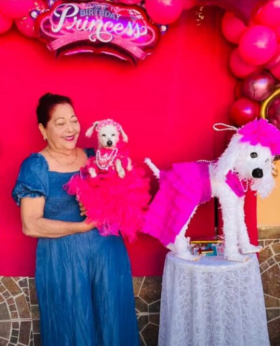 Mujer cargando en brazos a una perrita usando un vestido