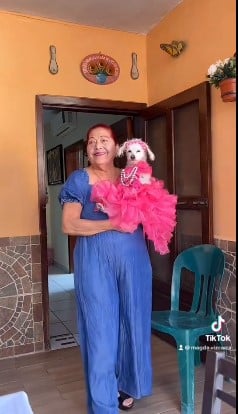 Mujer cargando en brazos a una perrita usando un vestido