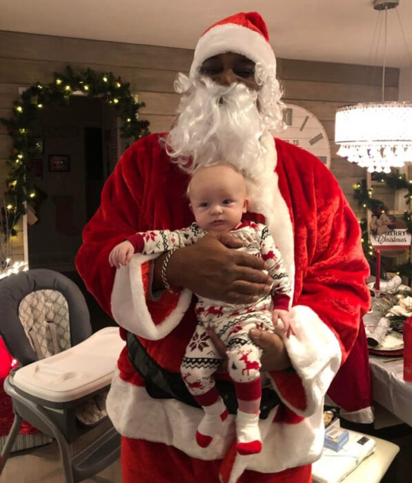 hombre vestido de Santa Claus cargando a un bebé 