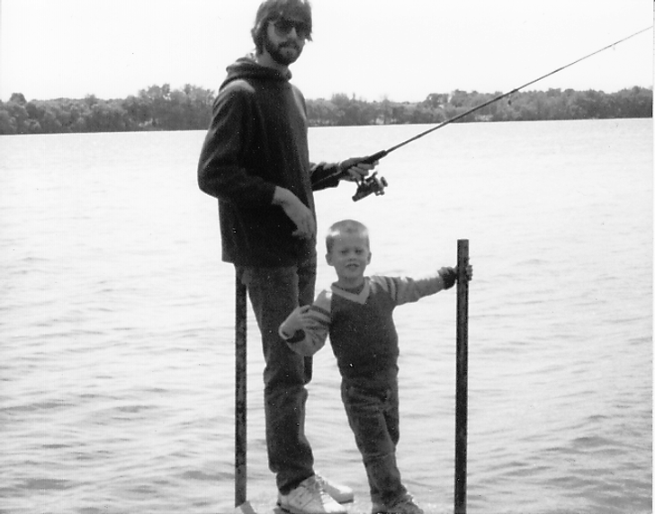 foto en blanco y negro de un niño pescando a lado de su padrastro 