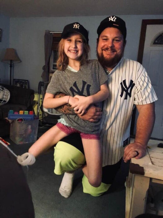 Hombre cargando a su hijastra vestidos con un jersey de los Yankes de New York