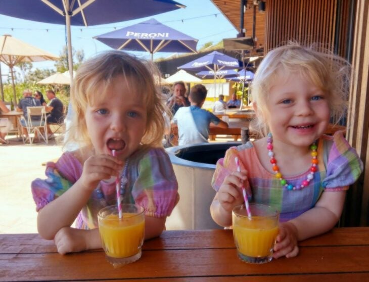 imagen de dos hermanas gemelas tomando jugo en un restaurant