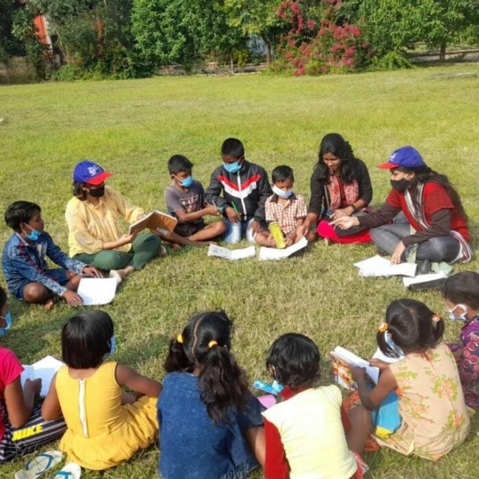 Niños sentados formando un círculo tomando clases en un jardín 