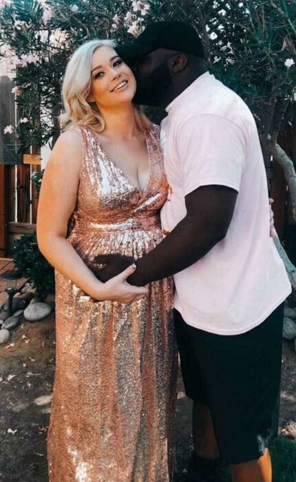 Woman hugging and kissing her husband while posing for a photo 