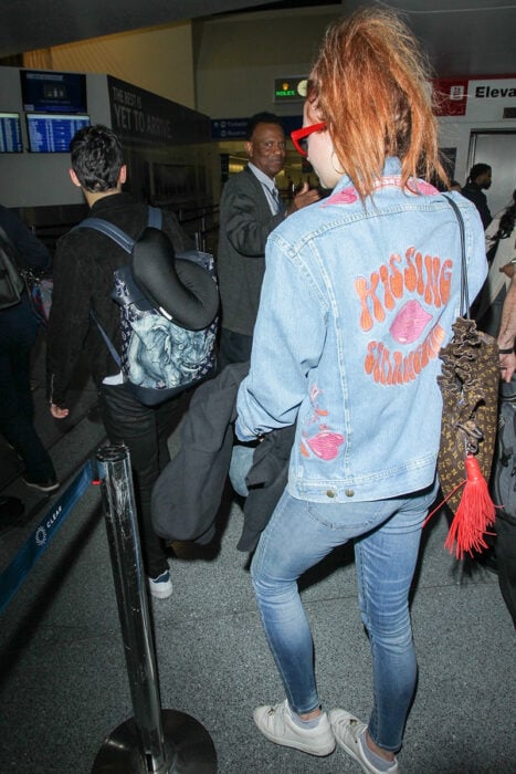 Sophie Turner caminando detrás de Joe Jonas portando chamarra de DNCE