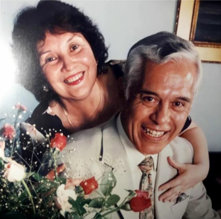 Fotografía de abuelos abrazados; Al soplar las velas del pastel, abuelo saca foto de su esposa; es su primer cumple sin ella