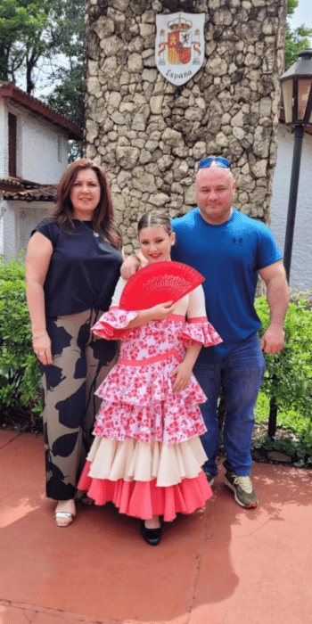 Girl in the middle of her parents in a school 