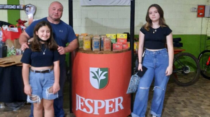 man accompanied by his two daughters at a shelf offering his merchandise 