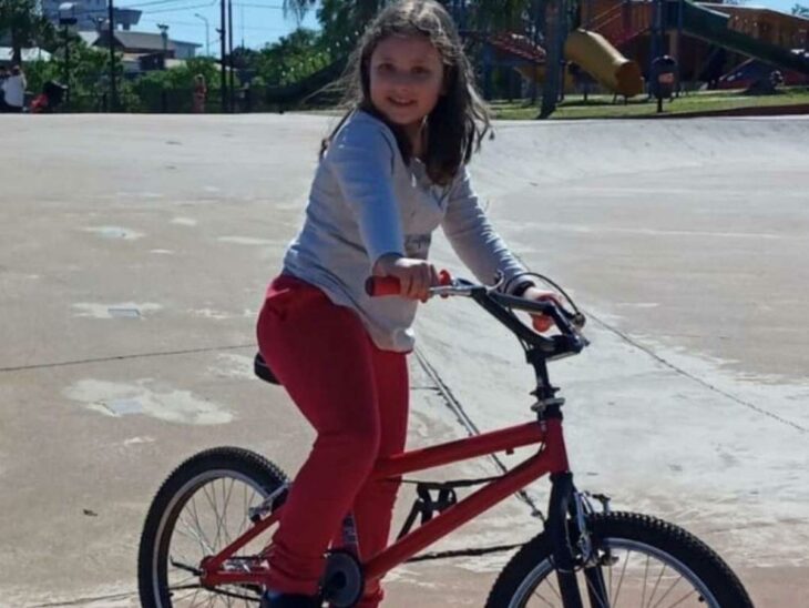 niña montada sobre una bicicleta en una calle 
