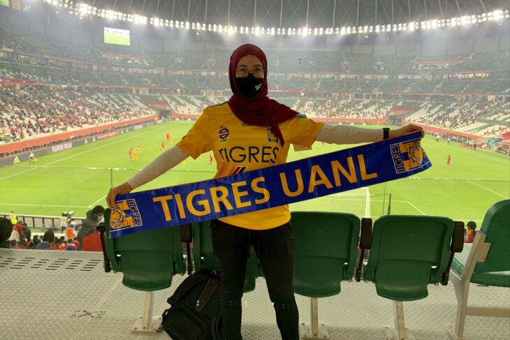 Paola Schietekat con una bandera del Trigres UANL en un estadio de futbol