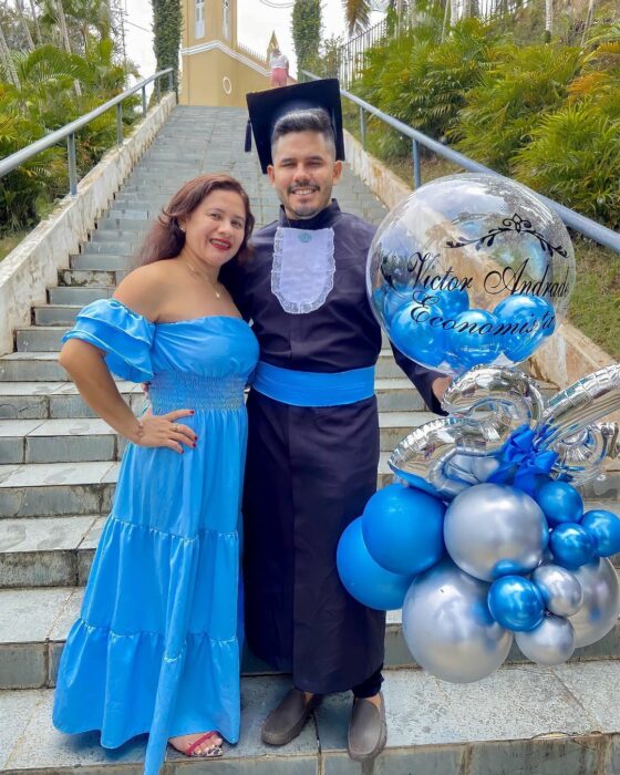 Fotografía de un joven recién graduado a lado de su mamá 