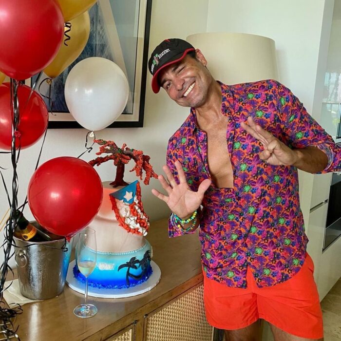 Cantante Chayanne posando a lado de un pastel de cumpleaños