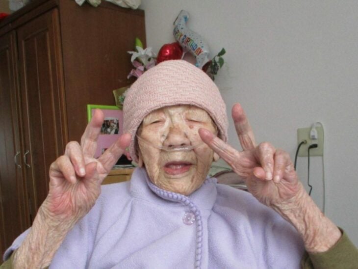 Japonesa Kane Tanaka, haciendo la señal de la V con sus dos manos en una casa de ancianos en Japón