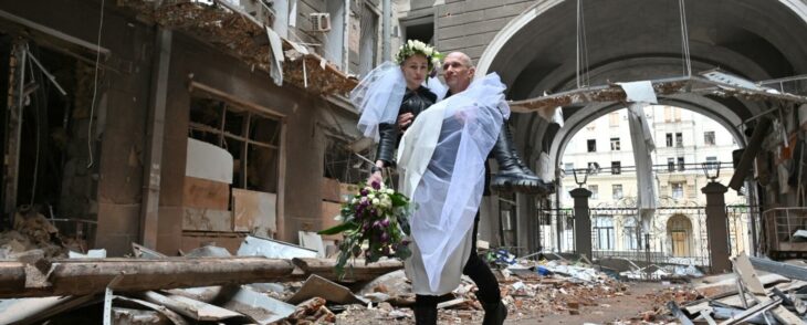 hombre cargando a su esposa recién casados en medio de los escombros de un edificio en Ucrania 