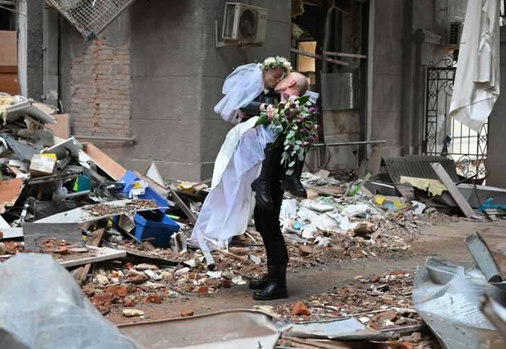 pareja de novios ucranianos en medio de sus sesión de fotos en un edificio derrumbado por los bombardeos de Rusia 