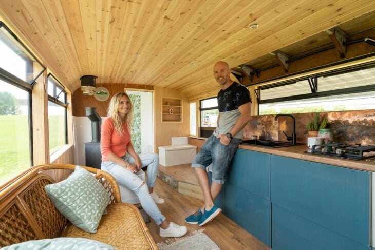 photograph of a married couple standing inside a bus converted into a house 