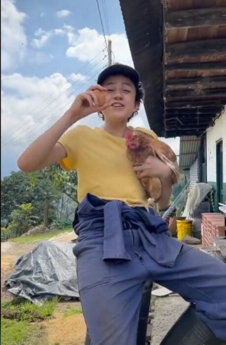 Captura de pantalla de un niño cargando una gallina y mostrando un huevo 