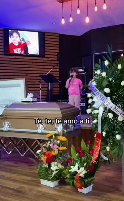 Girl singing in front of her grandfather's coffin at the funeral 