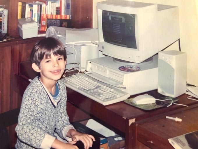 Chico frente a una computadora sonriendo 