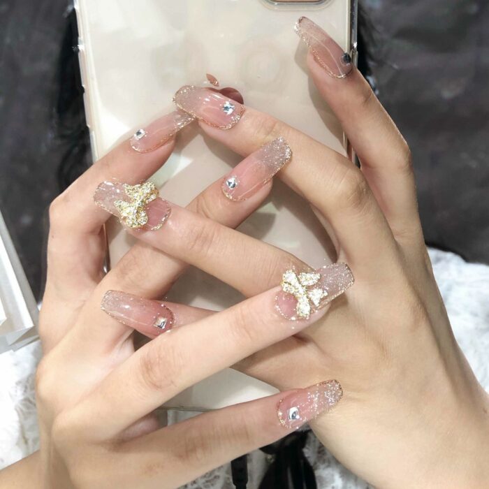 uñas acrílicas transparentes de una mujer sosteniendo un celular 