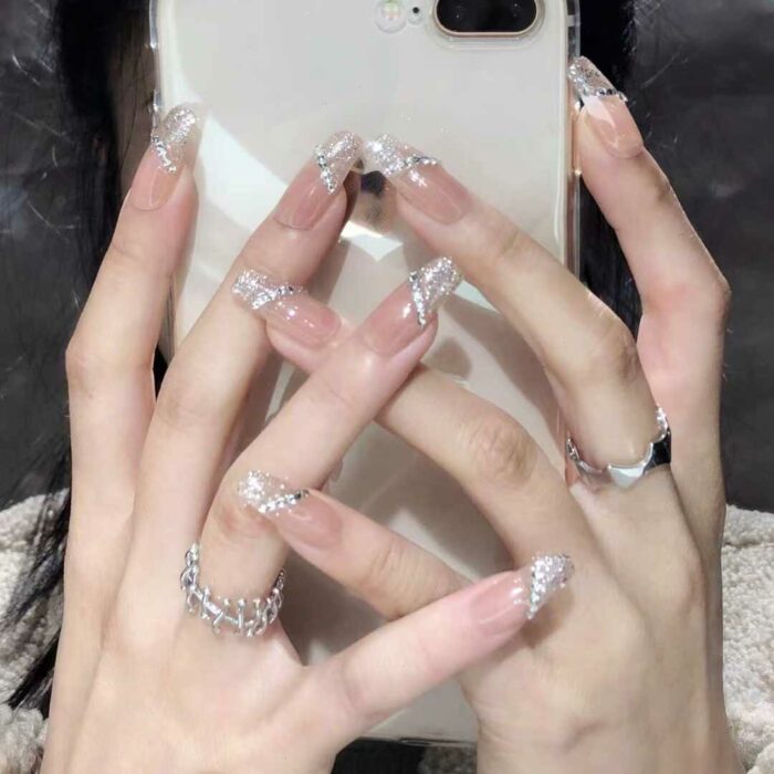 uñas transparentes con gris sosteniendo un iPhone