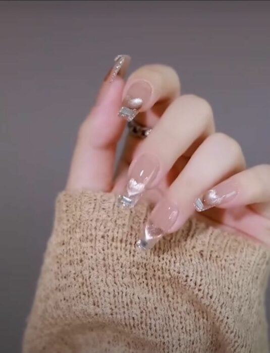 mano de una chica mostrando uñas con decoración con dorada 