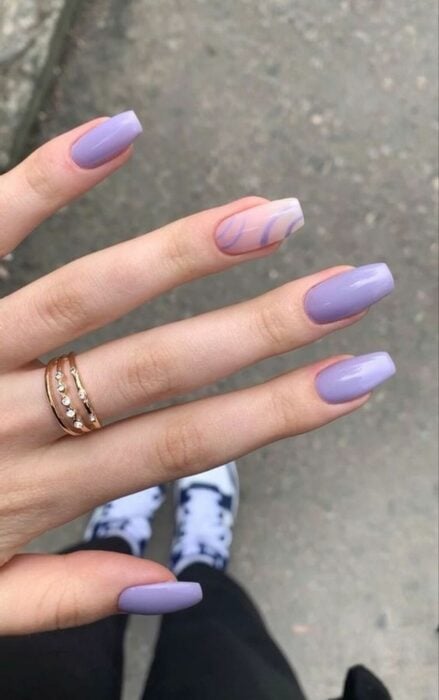 uñas acrílicas color lila con una en color diferente 