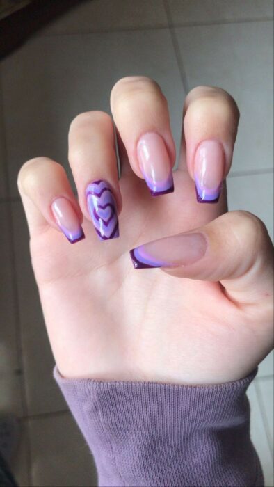 uñas acrílicas con estilo francés en color morado con un detalle de corazón 