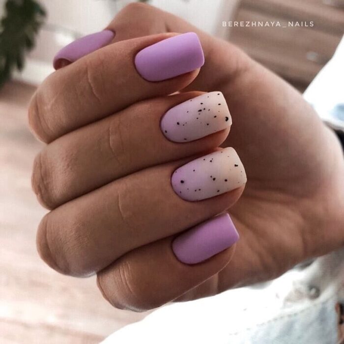 uñas acrílicas minis en color lila con dos blancas con detalles negros 