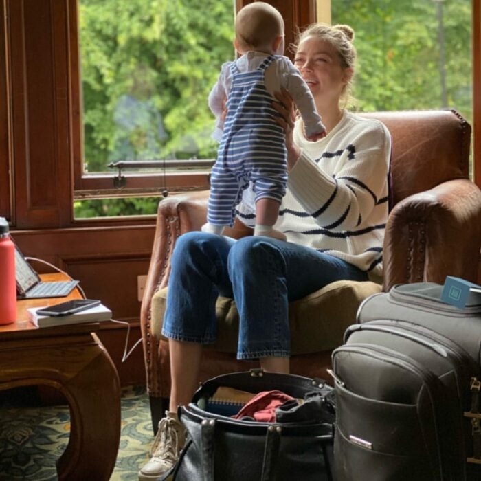 Actriz Amber Heard sentada en un sillón cargando a su pequeña hija 
