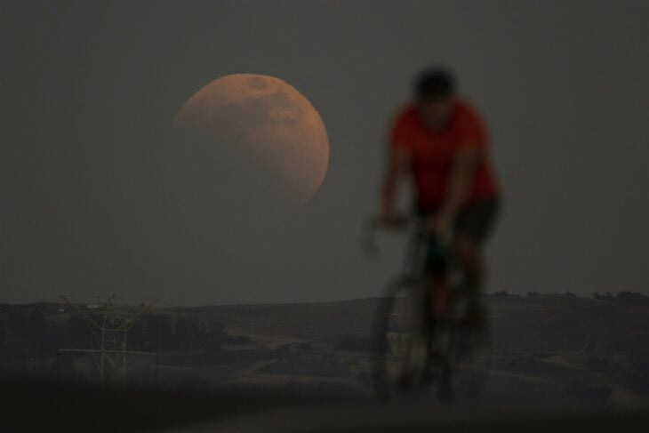 cyclist in front of the moon during the lunar eclipse 2022 in Irwindale in California, United States