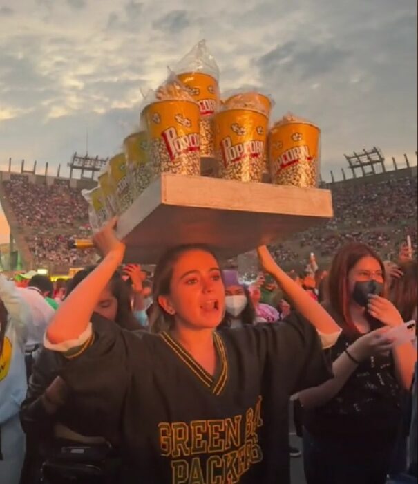 chica en un concierto con una charola de palomitas sobre la cabeza