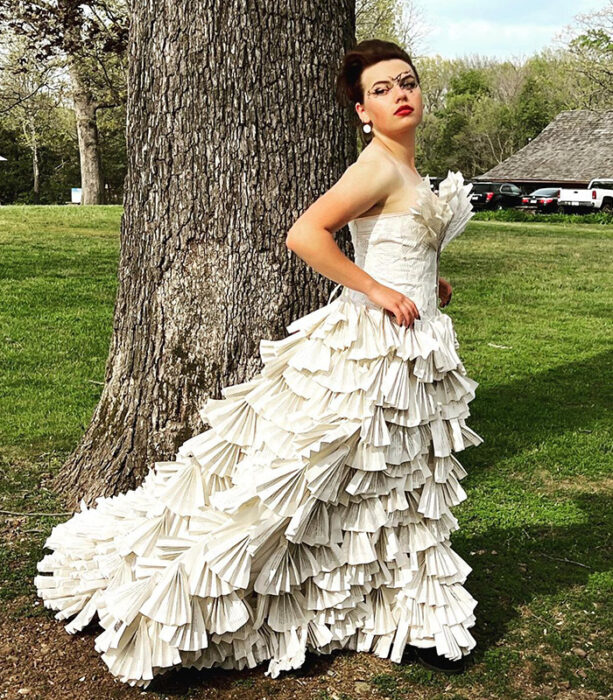 Girl posing in a tree with a dress made with book pages 