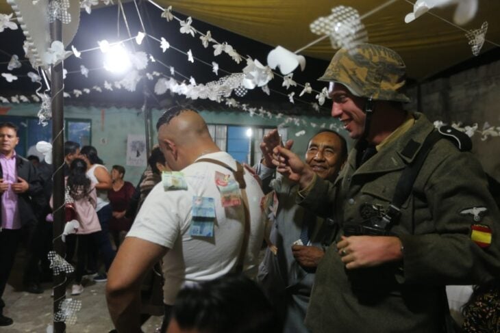hombres vestidos de soldados poniendo billetes a un hombre en la fiesta de su boda 