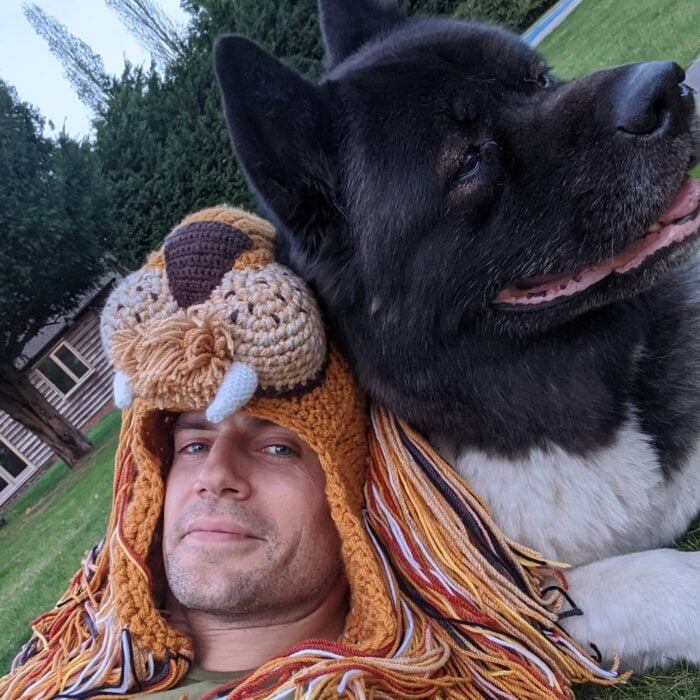 Henry Cavill a lado de su perro con un gorro en forma de león 