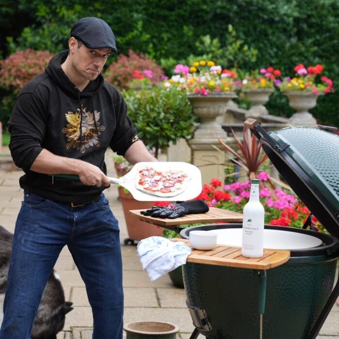 Foto de Henry Cavill frente a un asador haciendo una pizza 