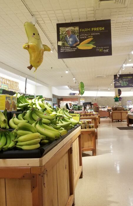 Estantes de fruta en el supermercado con globos de acuerdo a la fruta y verdura