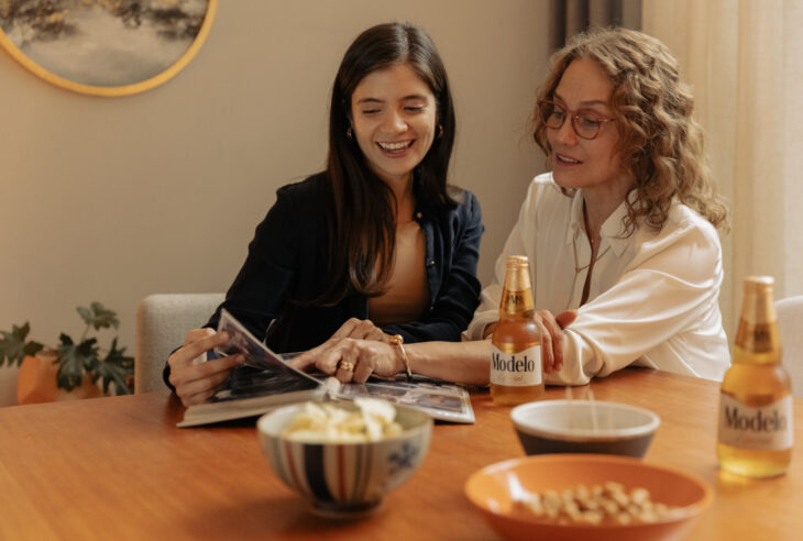 Mamá e hija sentadas a la mesa viendo álbum de fotos y riendo