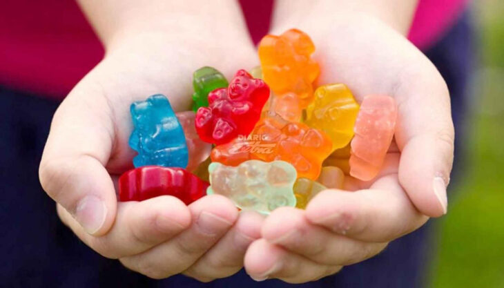 manos de un niño con algunas gomitas de colores sobre ellas 